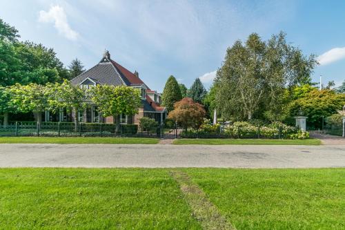 a house with a grass yard and a driveway at Logies De Houtdijk in Harich