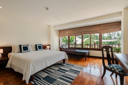 a bedroom with a bed and a desk and a window at Arinara Beach Resort Phuket - SHA Extra Plus in Bang Tao Beach