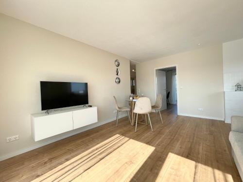 una sala de estar con TV de pantalla plana en un armario blanco en FeWo small Penthouse Lake of Constance with large terrace, en Friedrichshafen