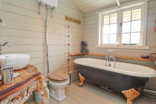 a bathroom with a tub and a toilet and a sink at Wild Rose Retreat in Ashford