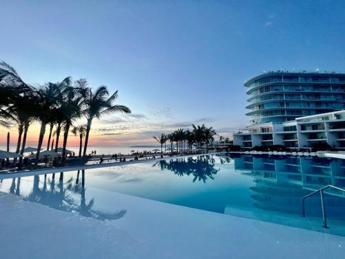 a large swimming pool with palm trees and a building at AriaOcean#410 in Nuevo Vallarta