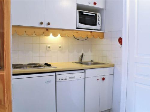une petite cuisine avec un évier et un micro-ondes dans l'établissement Appartement 2P 6 couchages, proche pistes, balcon, parking, animaux OK - FR-1-330-226, à Risoul