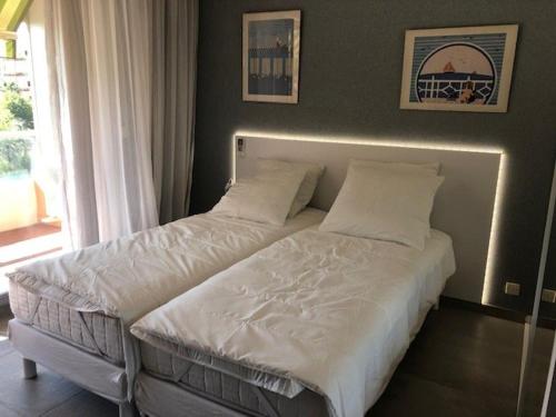 un lit avec des draps blancs et des oreillers dans une chambre dans l'établissement Charmant appart rénové au Lavandou - Terrasse, Clim, Centre-ville - FR-1-308-123, au Lavandou