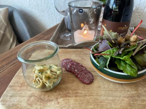 a table with a bowl of salad and a bottle of wine at Zeltplatz Großer Wald in Gaggenau