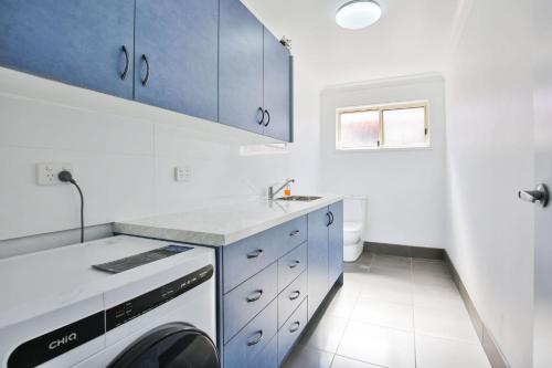 a kitchen with blue cabinets and a washing machine at Coastal Capers - Pet Friendly - 10 Mins Walk to Beach in Culburra Beach