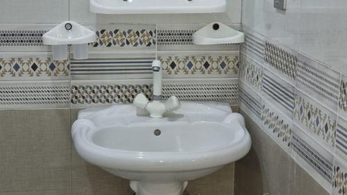 a bathroom with a white sink and a faucet at Karachi Guest House - Gulshan in Karachi