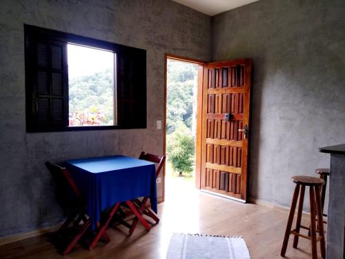 un comedor con una mesa azul y una ventana en Flats vista bela com vista da montanha, en Paraty