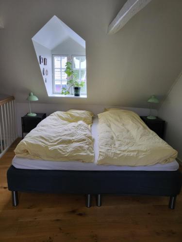 an unmade bed in a bedroom with a window at Det lille hus in Middelfart