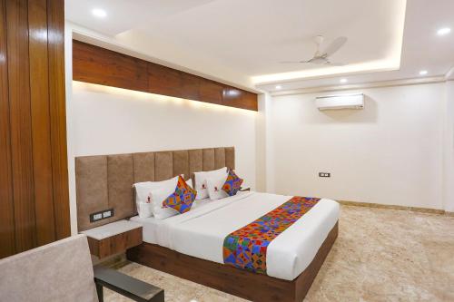 - une chambre avec un grand lit et une chaise dans l'établissement FabHotel Golf Inn Golf Course Road Gurgaon, à Gurgaon