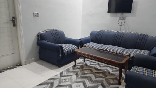 a living room with two blue couches and a coffee table at Karachi Guest House - Gulshan in Karachi