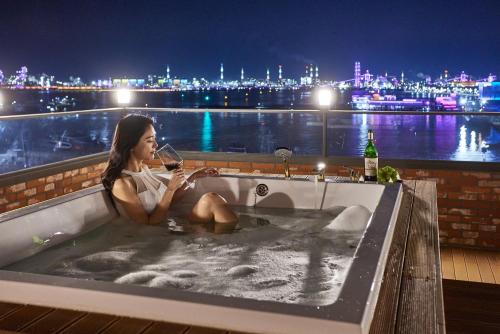 a woman sitting in a bath tub with a glass of wine at Browndot Terrace Pohang Passenger Terminal in Pohang