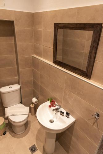 a bathroom with a sink and a toilet and a mirror at Kentavros Hotel in Agios Lavrentios