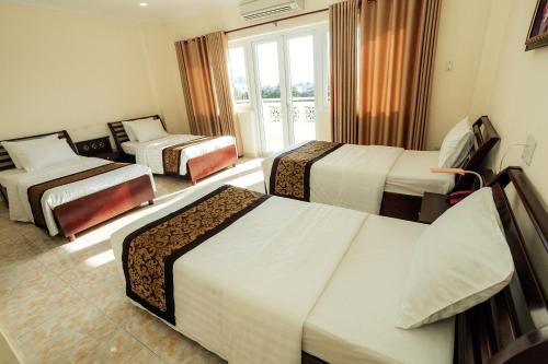 a hotel room with three beds and a window at Biet Dien Hotel in Buon Ma Thuot