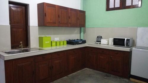 a kitchen with wooden cabinets and a sink at Hitchhike Backpackers in Mount Lavinia