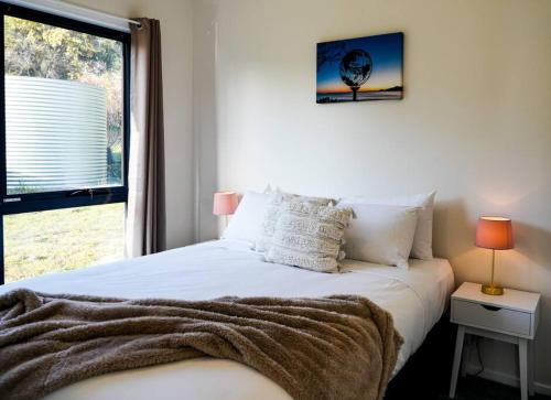 1 dormitorio con 1 cama blanca y ventana en Rockpool Cottage, en Lunawanna