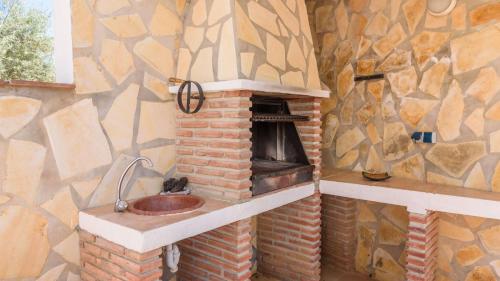 een badkamer met een stenen open haard en een wastafel bij Sierra Tejeda - Casa del Valle Alcaucín by Ruralidays in Alcaucín