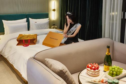 a woman talking on a cell phone next to a bed at Browndot Terrace Pohang Passenger Terminal in Pohang