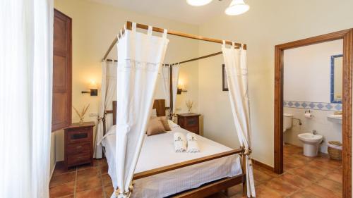 a bedroom with a canopy bed and a bathroom at Casa Rural Aire Fuente de Piedra by Ruralidays in Fuente de Piedra