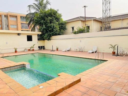 una piscina en un patio con sillas y un edificio en Elegant 3 bedrooms apartment ikoyi en Lagos