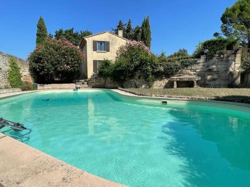 une grande piscine d'eau bleue en face d'une maison dans l'établissement Ancien moulin restaurer avec piscine, à Roquemaure