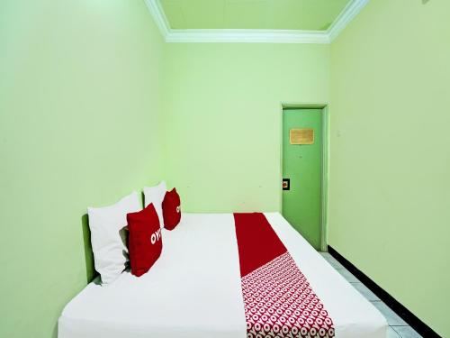 1 dormitorio con cama blanca y almohadas rojas en OYO 2708 Hotel Kemuning Syariah, en Ramekasan