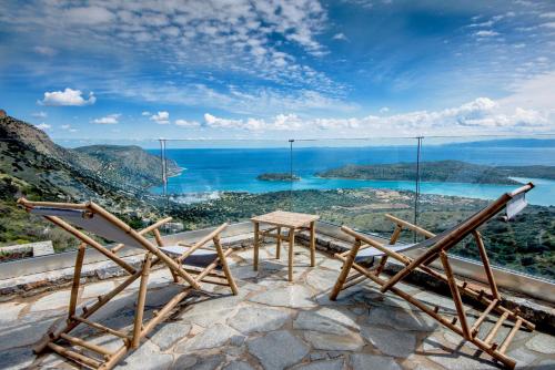 a table and chairs on top of a mountain with the ocean at La Villa Havgas in Elounda