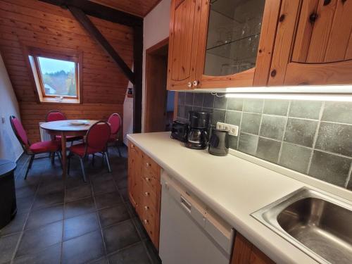 a kitchen with a sink and a table with chairs at Ferienhaus Regner „Das Anwesen am See“ **** in Feldberg