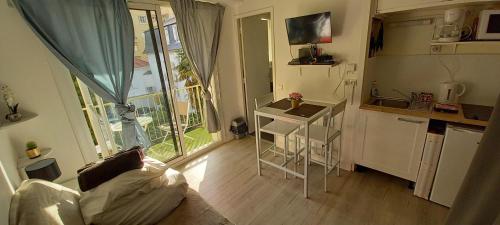 uma pequena sala de estar com um sofá e uma cozinha em Au petit repère palois -studio - centre ville-balcon-WIFI FIBRE em Pau