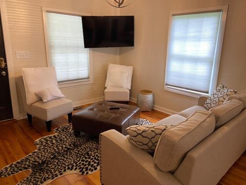 a living room with a couch and two chairs and a flat screen tv at Frank Howard 111 Farmhouse in Clemson