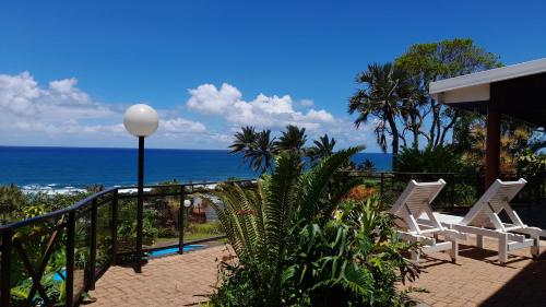 a balcony with two white chairs and the ocean at Wailana lodge in Ramsgate