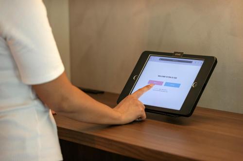 a person is pointing at a tablet on a desk at Hotel Ten to Ten in Sapporo