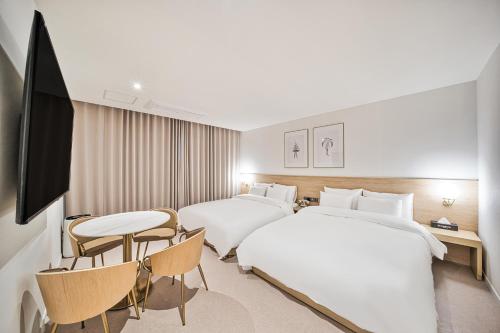 a hotel room with two beds and a table and chairs at Browndot Terrace Pohang Passenger Terminal in Pohang
