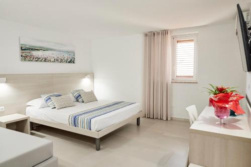 a white bedroom with a bed and a table at Kalsa Sicilian Rooms in Partinico