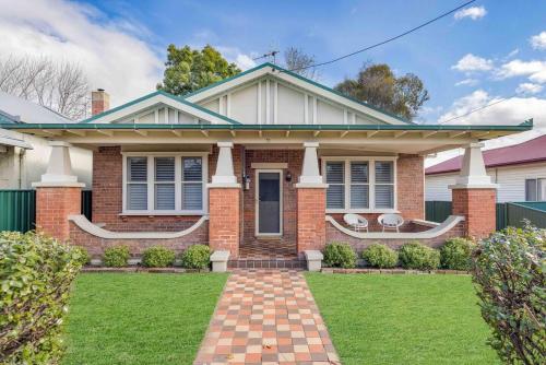 a brick house with a lawn in front of it at Currawong Bungalow - An Idyllic Group Stay in Town in Mudgee