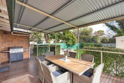 a patio with a wooden table and chairs at Currawong Bungalow - An Idyllic Group Stay in Town in Mudgee