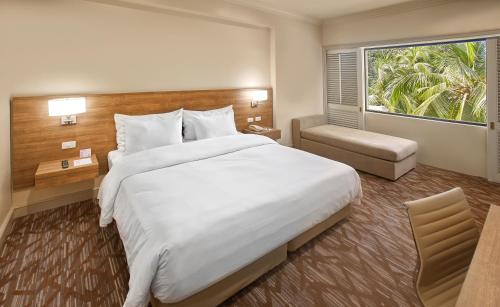 a hotel room with a large bed and a window at Quest Plus Conference Center, Clark in Clark