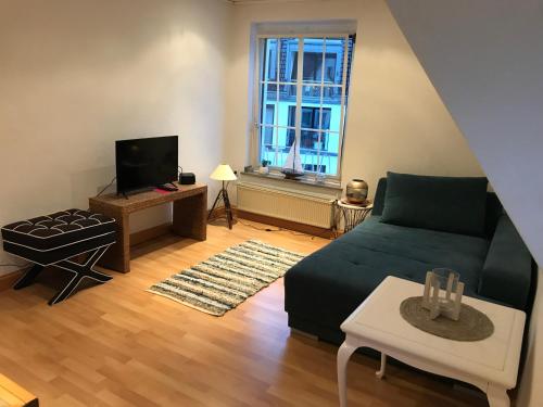 a living room with a green couch and a window at Generations Holiday City Flat in Attendorn