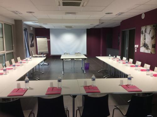 a conference room with tables and chairs and a screen at The Originals City, Hôtel des Lys, Dreux in Dreux