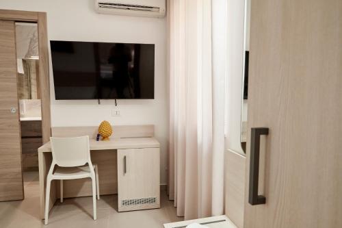 a white desk with a chair and a television on a wall at Kalsa Sicilian Rooms in Partinico