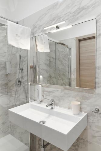 a white bathroom with a sink and a mirror at Kalsa Sicilian Rooms in Partinico