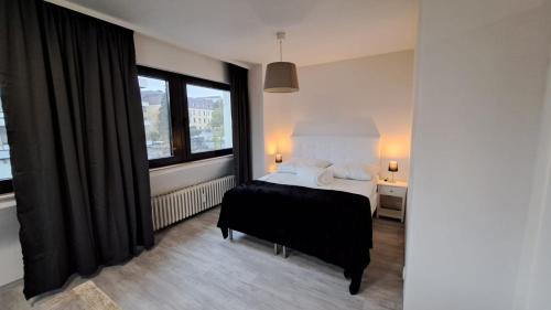 a bedroom with a bed and a desk and windows at Wohnung am Krankenhaus, Ruhr, Wasserbhf. in Mülheim an der Ruhr
