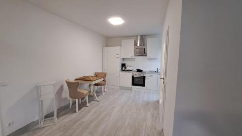 a kitchen with white cabinets and a table and chairs at Wohnung am Krankenhaus, Ruhr, Wasserbhf. in Mülheim an der Ruhr