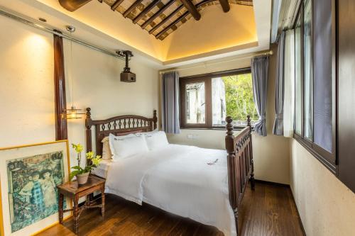 een slaapkamer met een groot wit bed en een raam bij Tongli 1917 Best South Inn in Suzhou