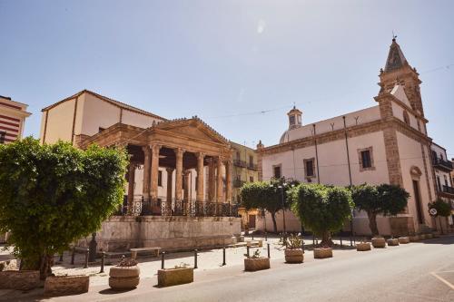 un vecchio edificio con alberi di fronte di Kalsa Sicilian Rooms a Partinico