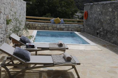 a pool with two chairs and a table and a swimming pool at Villa Praxithea BY APOKORONAS-VILLAS in Gavalochori