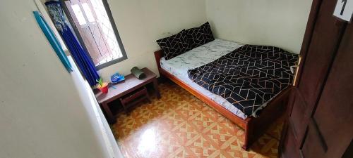 Dormitorio pequeño con cama y mesa en Cenggo Homestay en Ruteng