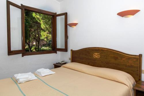um quarto com 2 camas e uma janela em Baia Delle Palme Beach em Santa Margherita di Pula