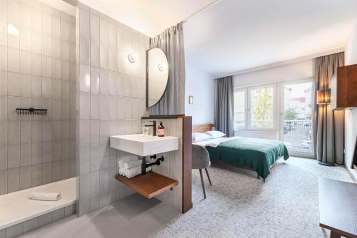a hotel room with a bed and a sink and a mirror at magdas HOTEL Vienna City - NEW OPENING AUTUMN 2022 in Vienna