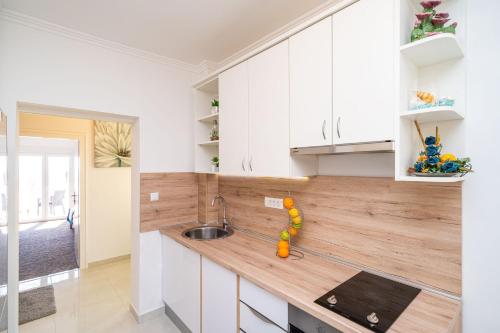 a kitchen with white cabinets and a wooden counter top at Apartments Blažević in Mlini