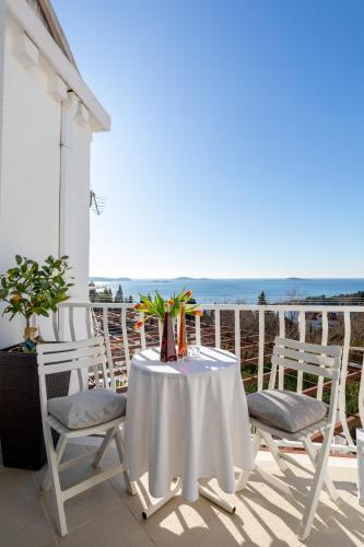 a table and chairs on a balcony with the ocean at Apartments Blažević in Mlini